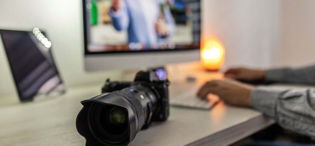 nonprofit volunteer management of photographer with zoom lens camera at desk with computer